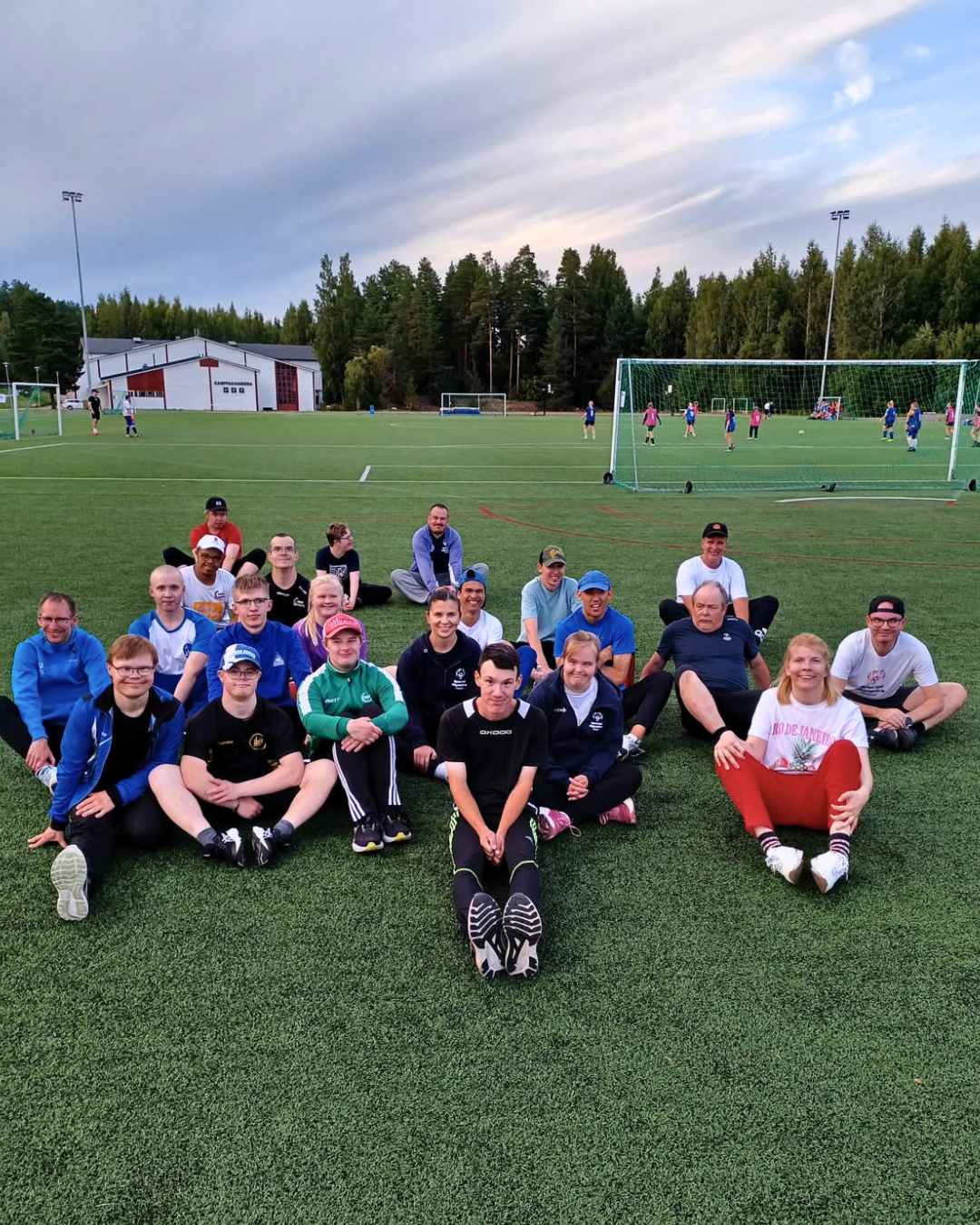 Yleisurheilijoita kentällä istumassa ja poseeraamassa kameralle.